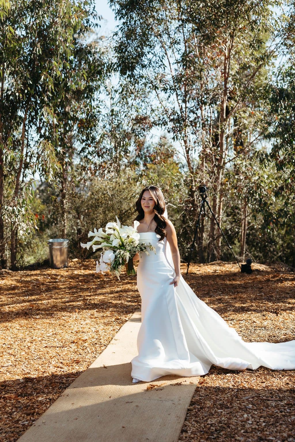 Ann walking down the aisle at The Cliffs, her bouquet of white orchids and her train behind her