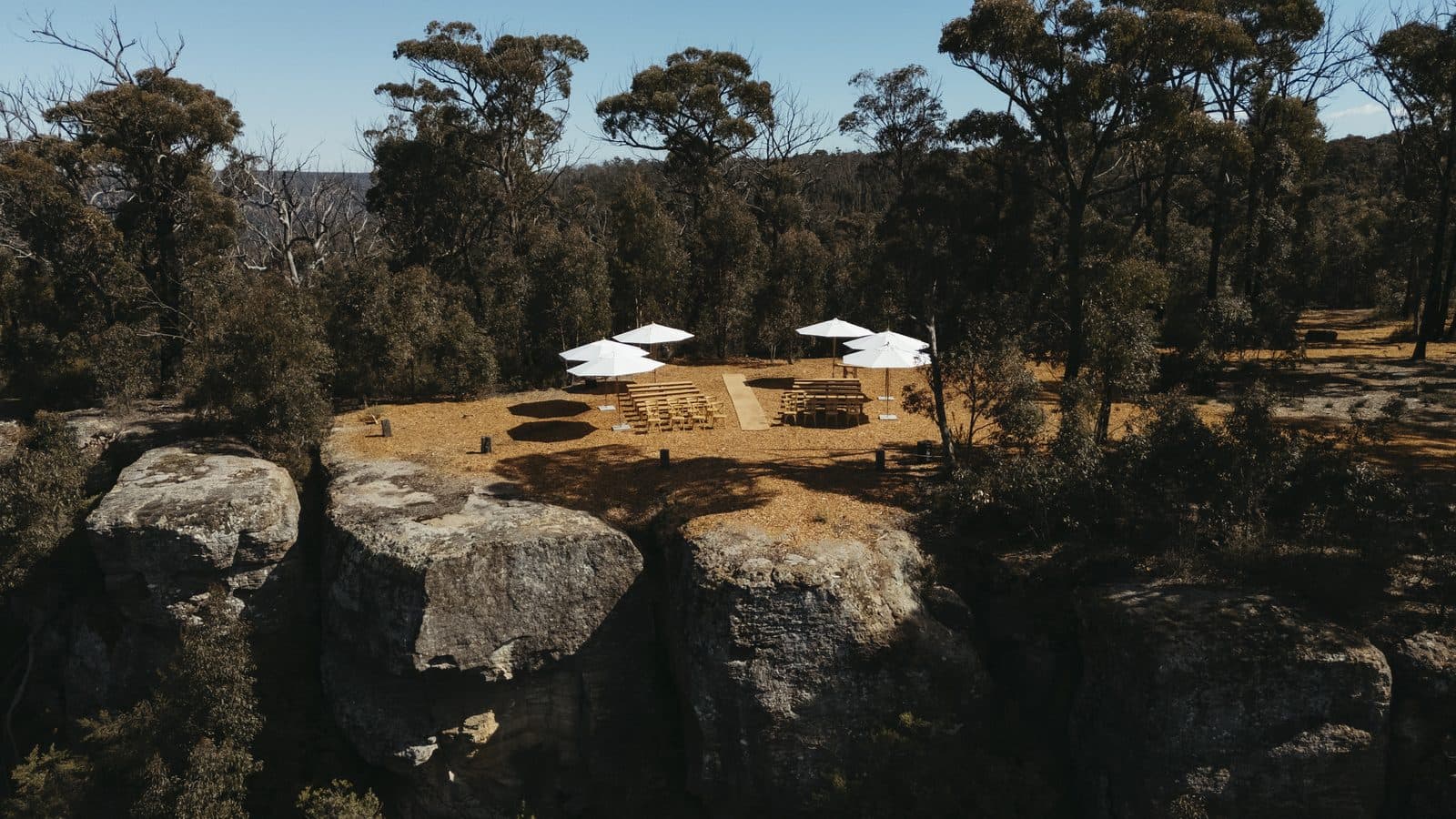 The ceremony site at The Cliffs from the air, white umbrellas over the benches on the sandstone above the gorge