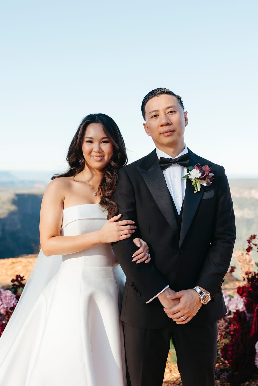 Ann and Winston arm in arm beside the ceremony florals at The Cliffs