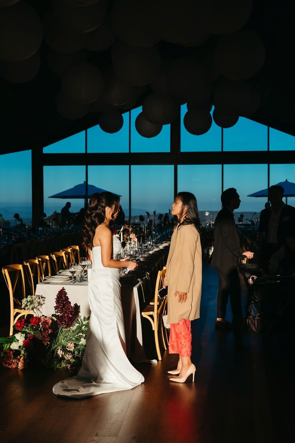 Ann in The Pavilion before dinner, the long tables set and the escarpment through the gabled glass
