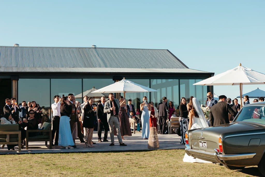 Guests gathered on the terrace of The Pavilion for cocktail hour, the Rolls-Royce parked on the lawn
