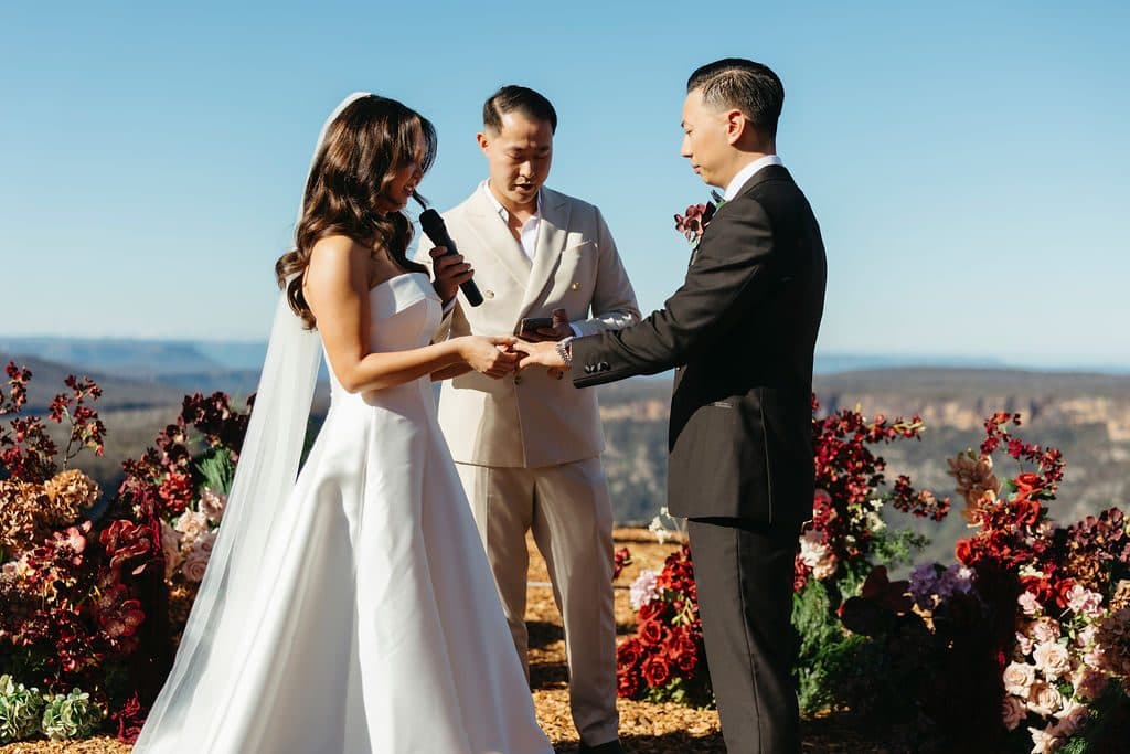 Ann and Winston holding hands through the vows at The Cliffs, florals and the gorge behind them