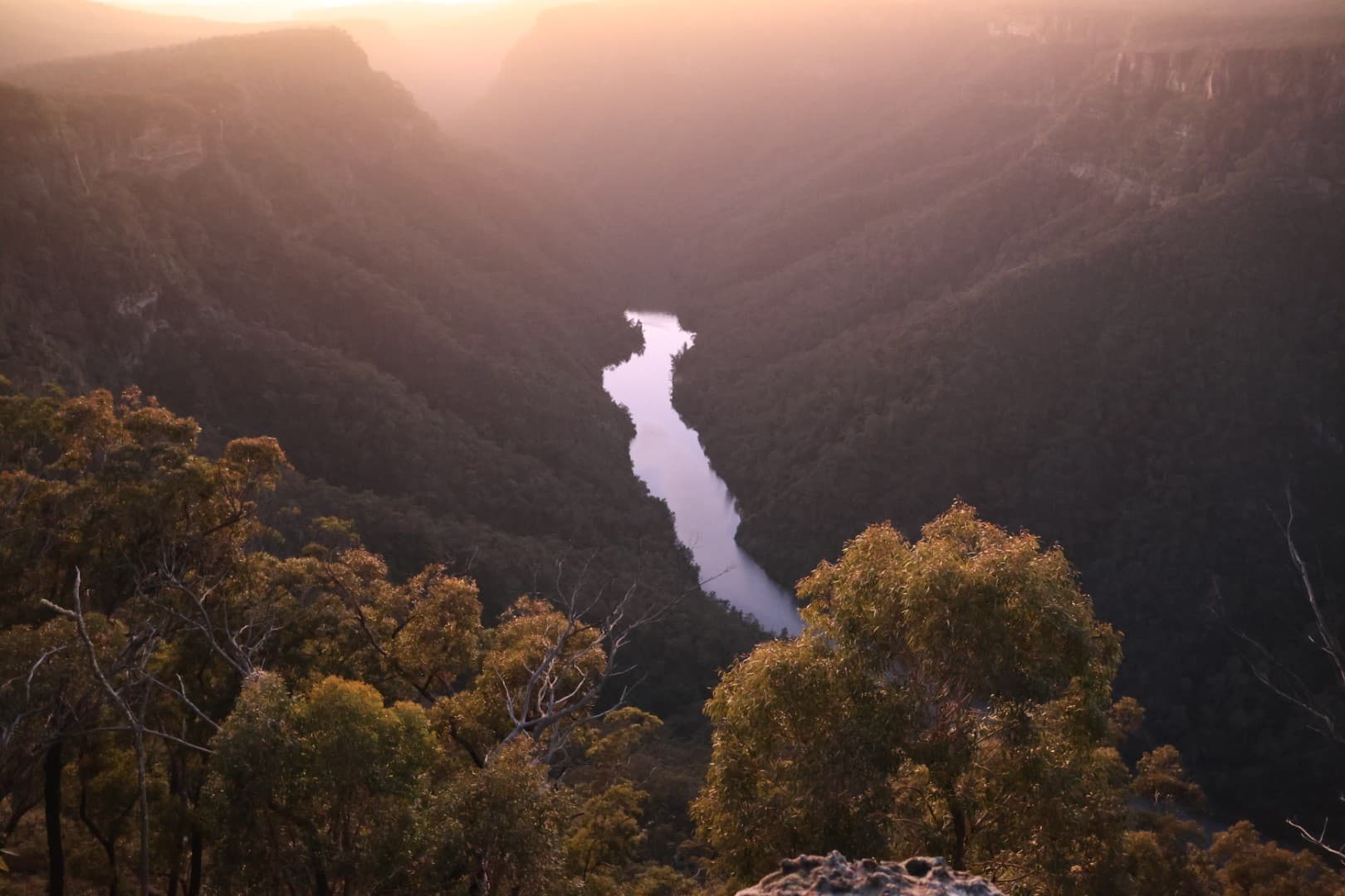 First light over the Shoalhaven gorge at Caoura Cliffs, the sun rising beyond the escarpment and the river glowing softly below