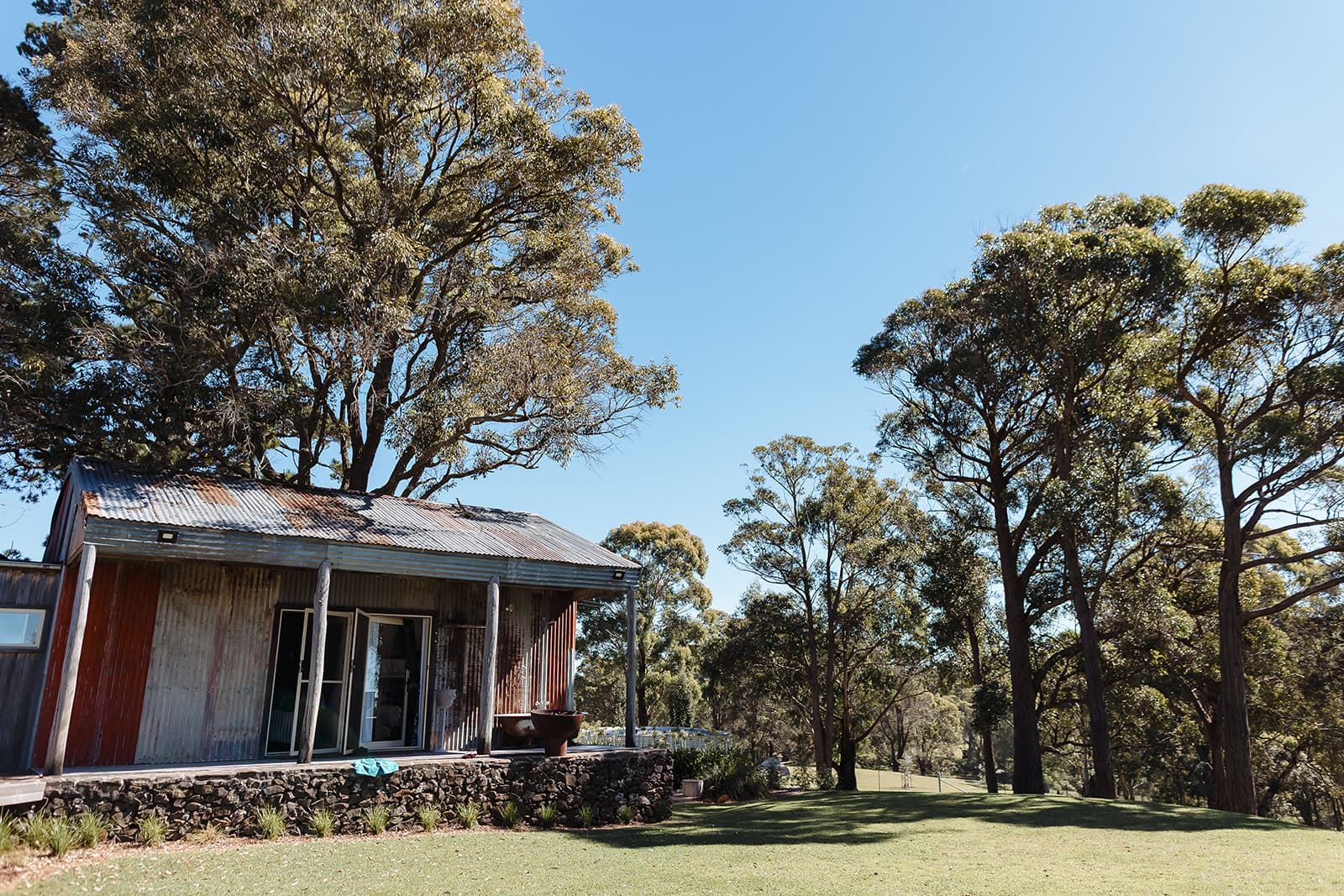The Homestead's corrugated-iron facade and stone garden wall at Caoura Cliffs, seen from the lawn