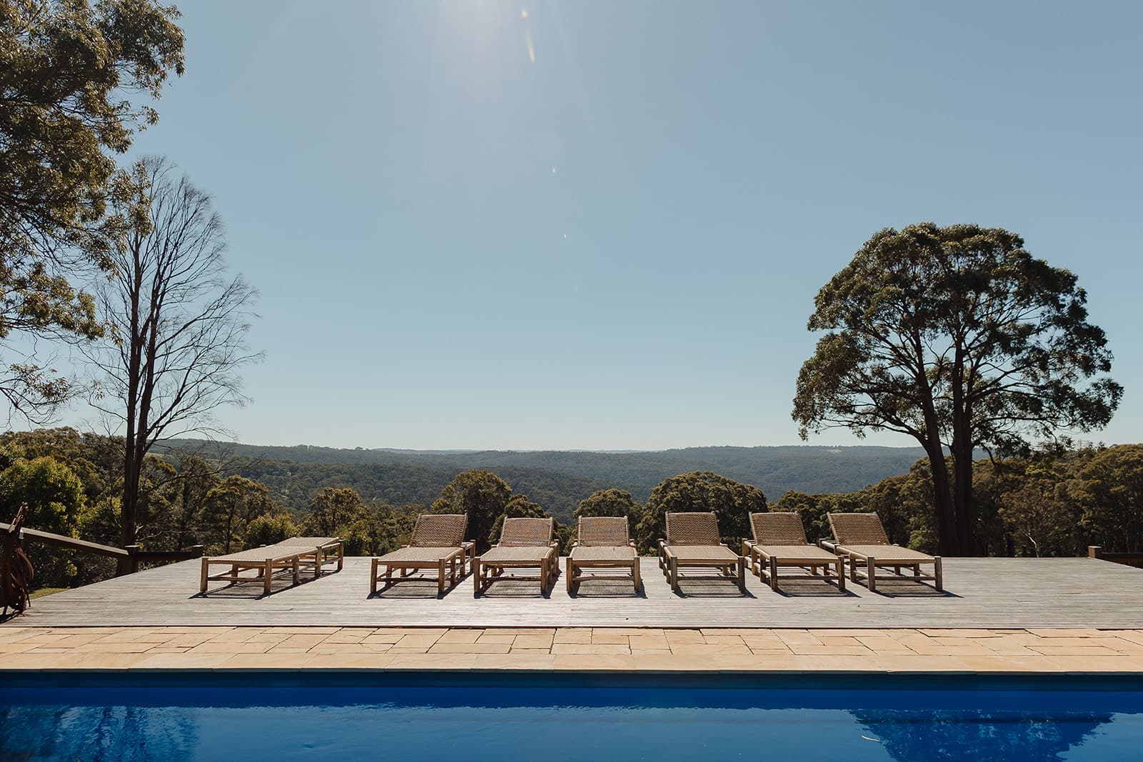 Sun loungers along the pool deck at The Homestead, looking out over the bushland ranges