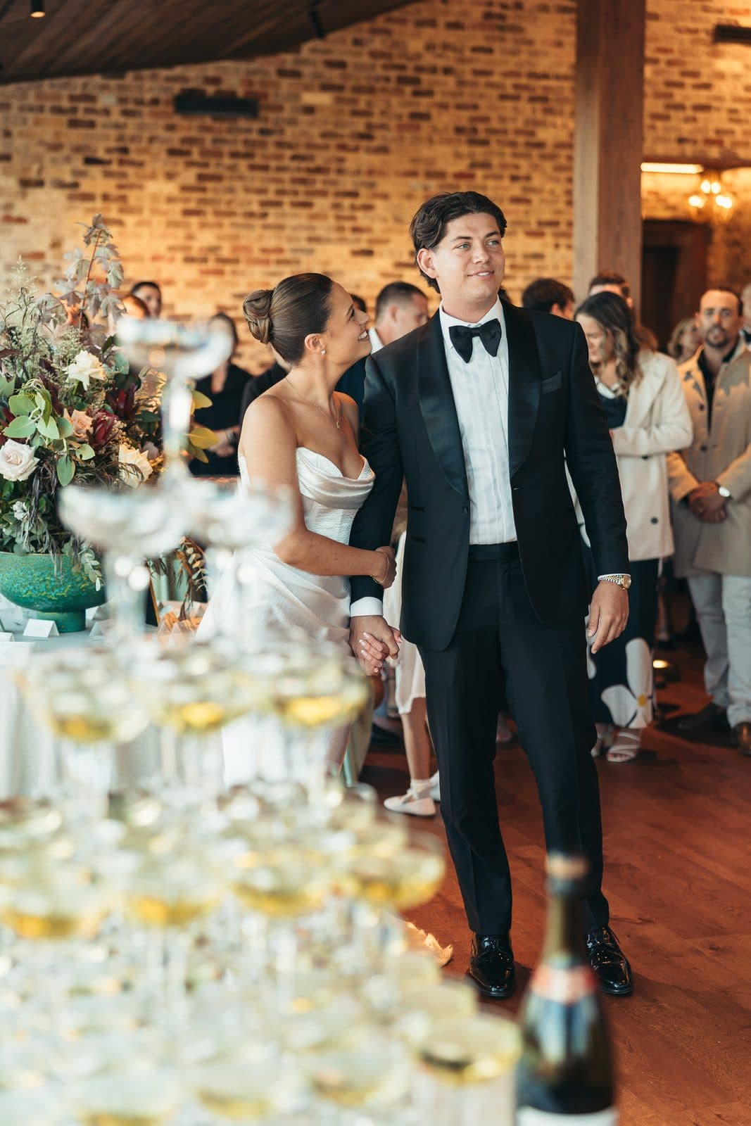 Ryan pouring the champagne tower in The Pavilion, Liv and the guests around him
