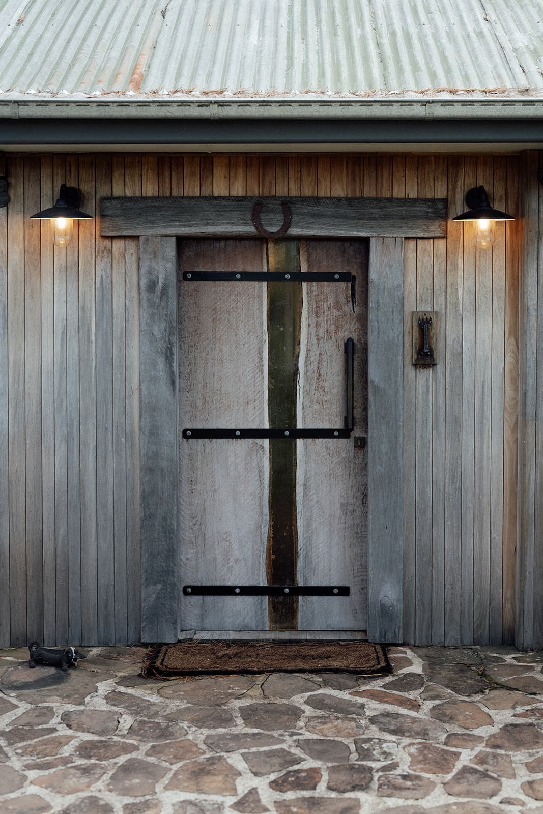 The Homestead's rustic timber barn door, framed by warm lantern light