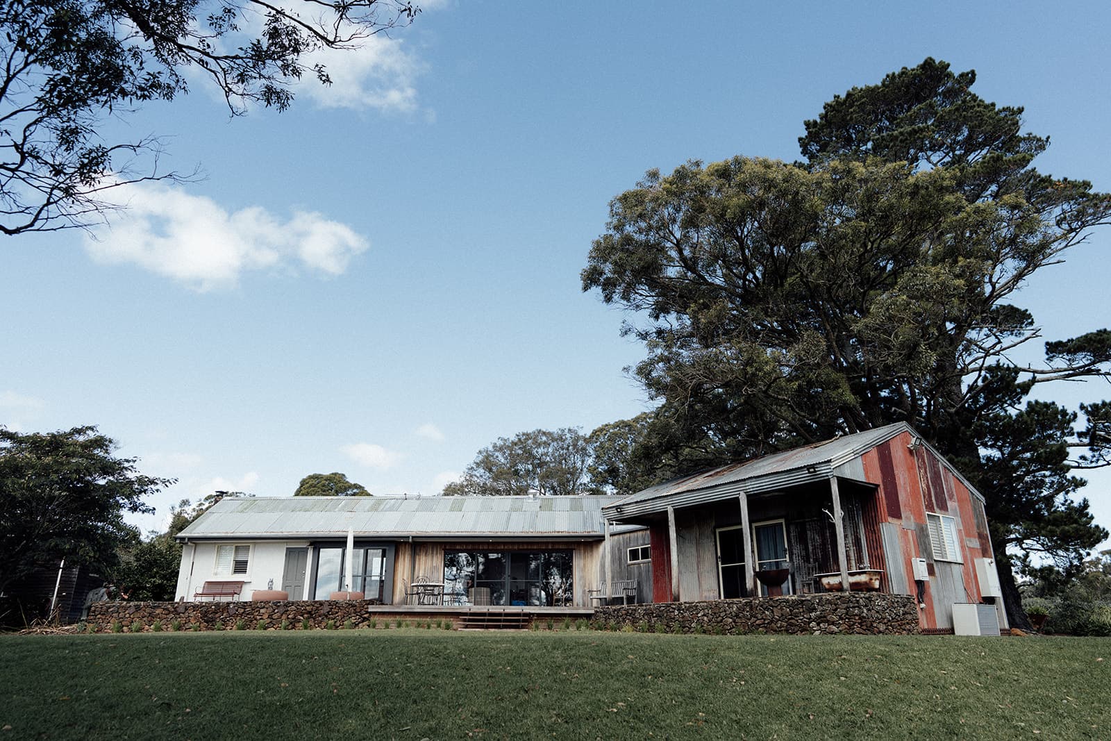 The Homestead and its corrugated-iron barn on the lawn beneath tall gums