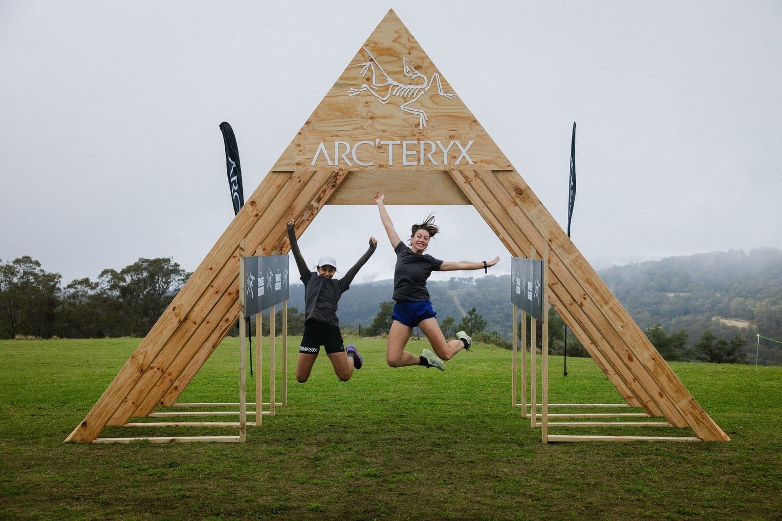 Two runners jumping under the arch at the finish