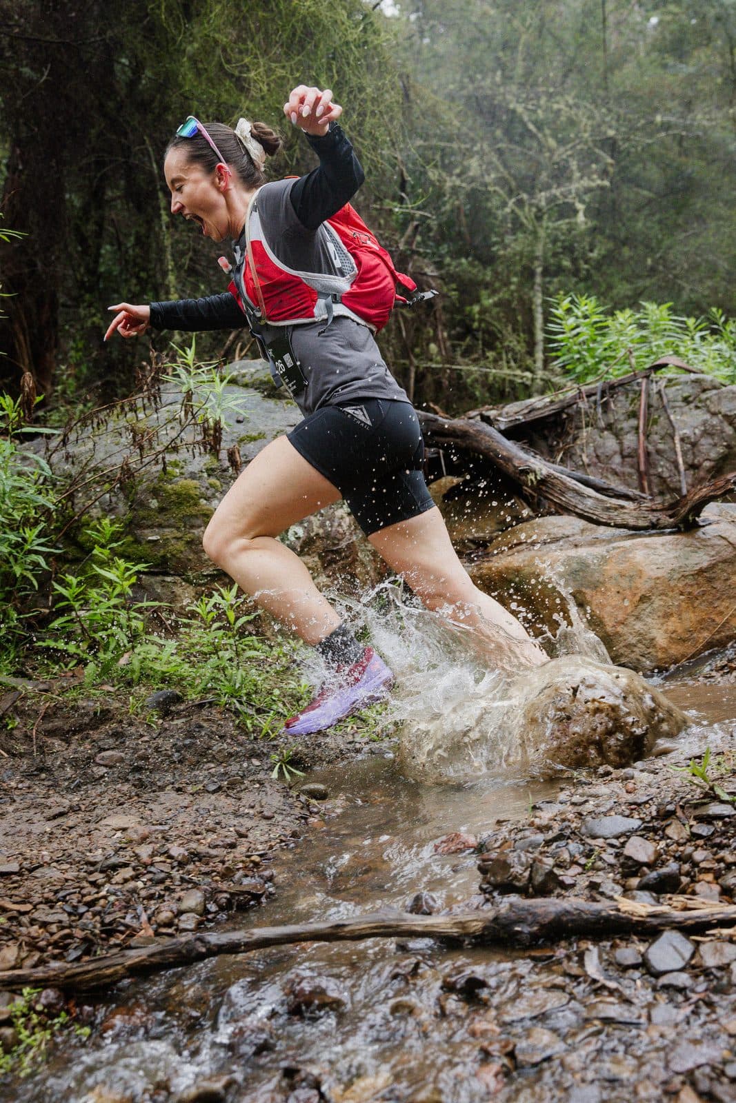 A runner splashing through a rock creek crossing in the bush