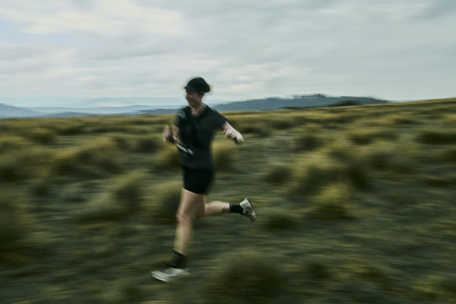 A runner blurred against open tussock grass