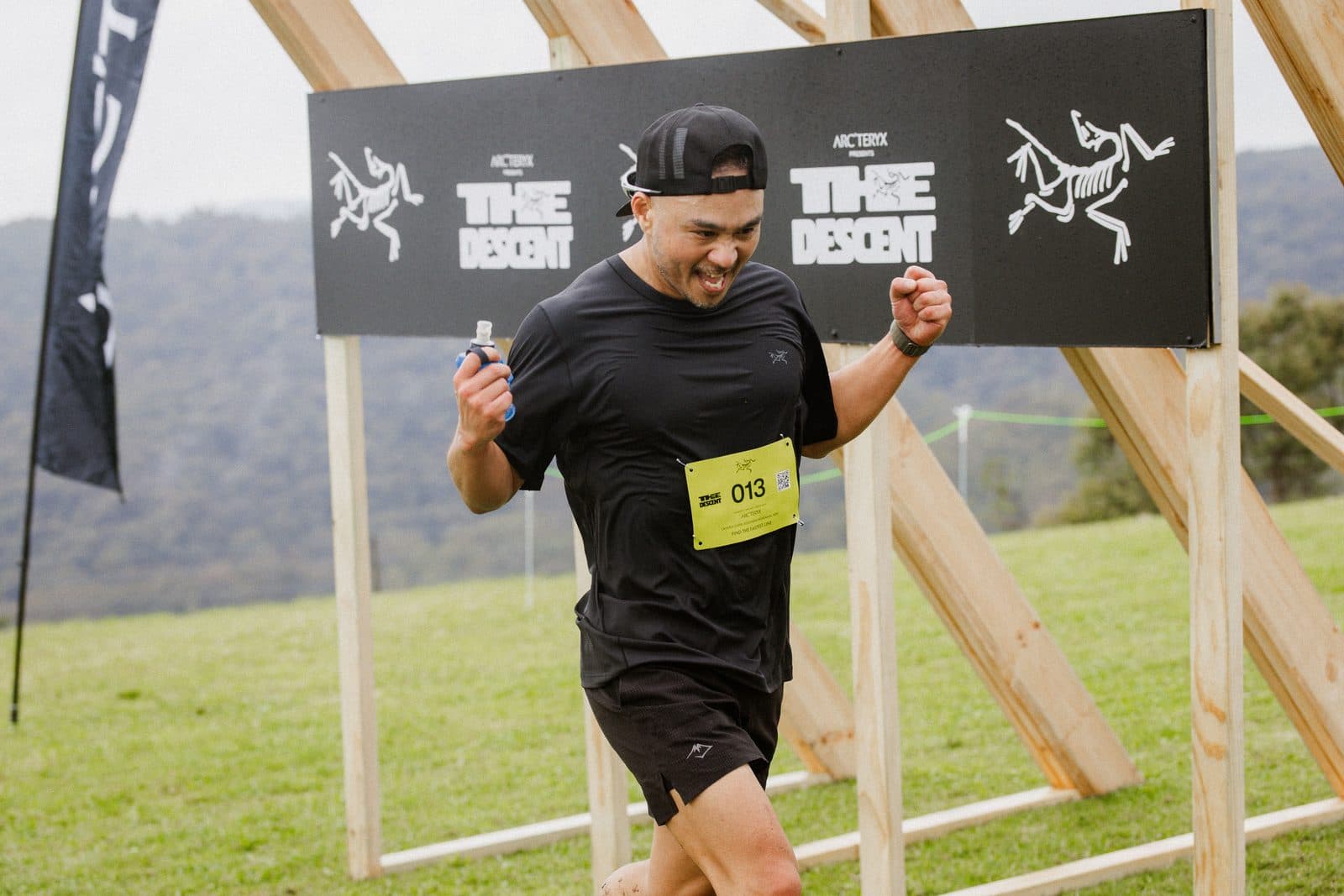 A runner crossing the finish under a banner reading The Descent