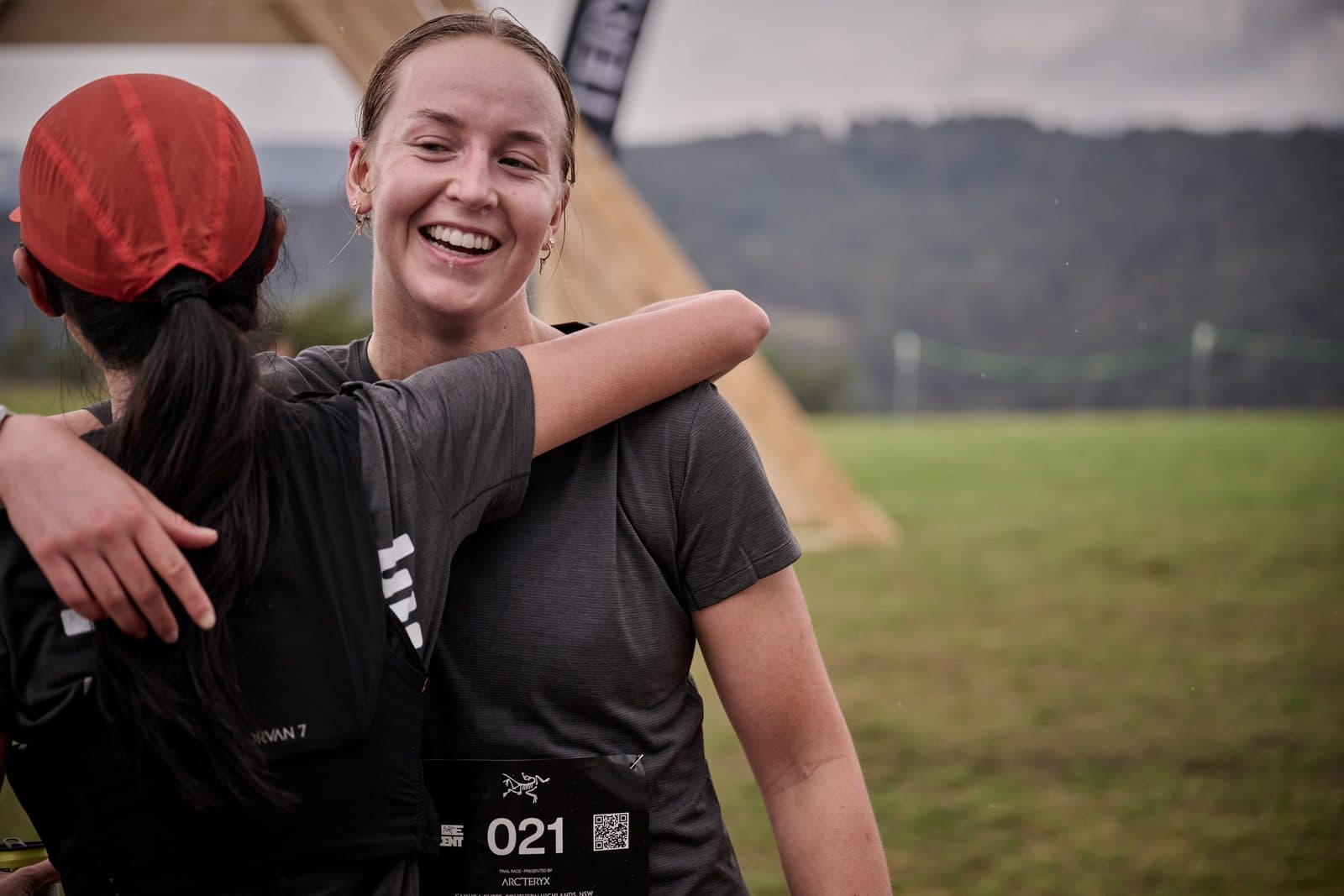Two finishers embracing on the lawn, the ranges behind