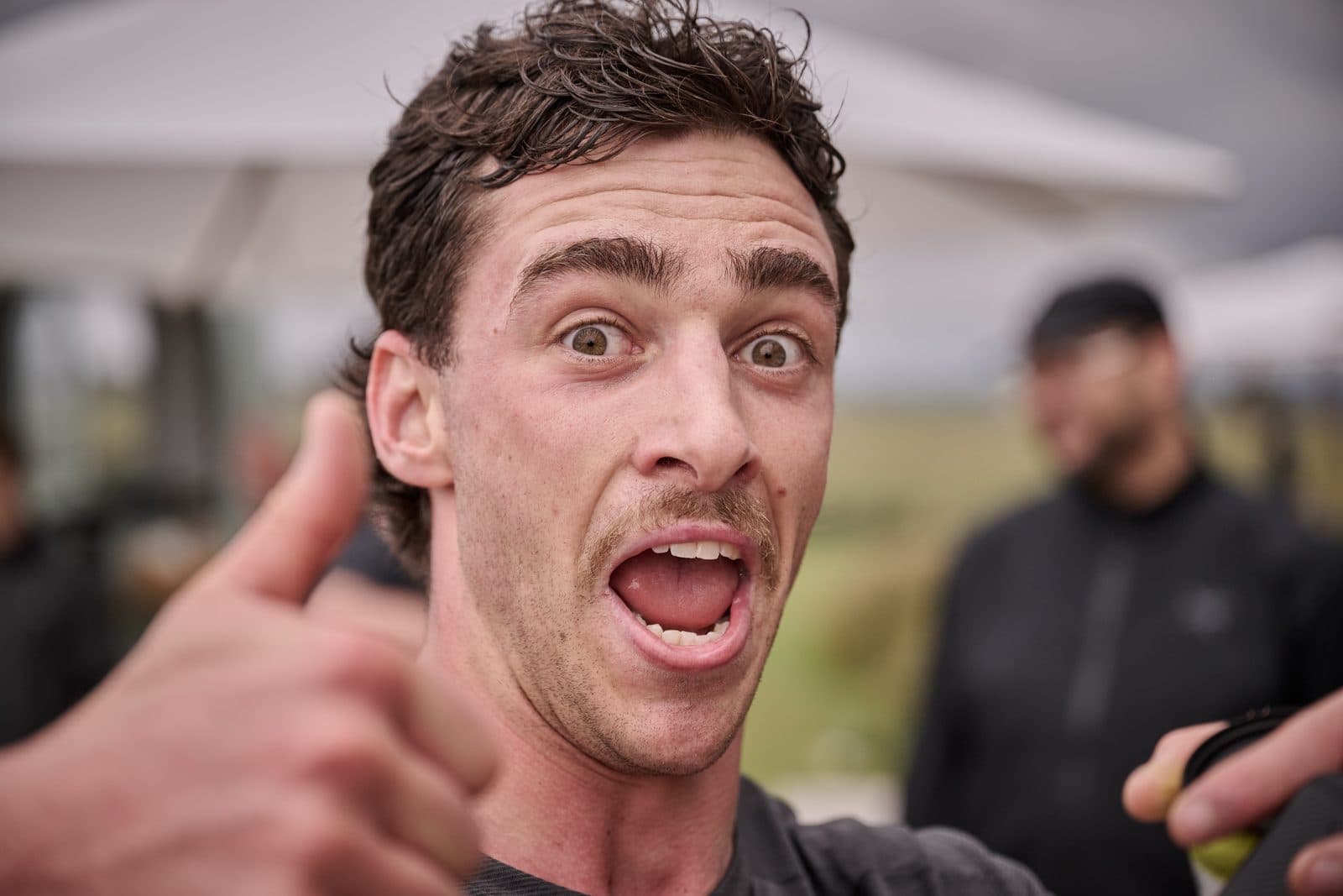 A finisher grinning into the camera with a thumbs up