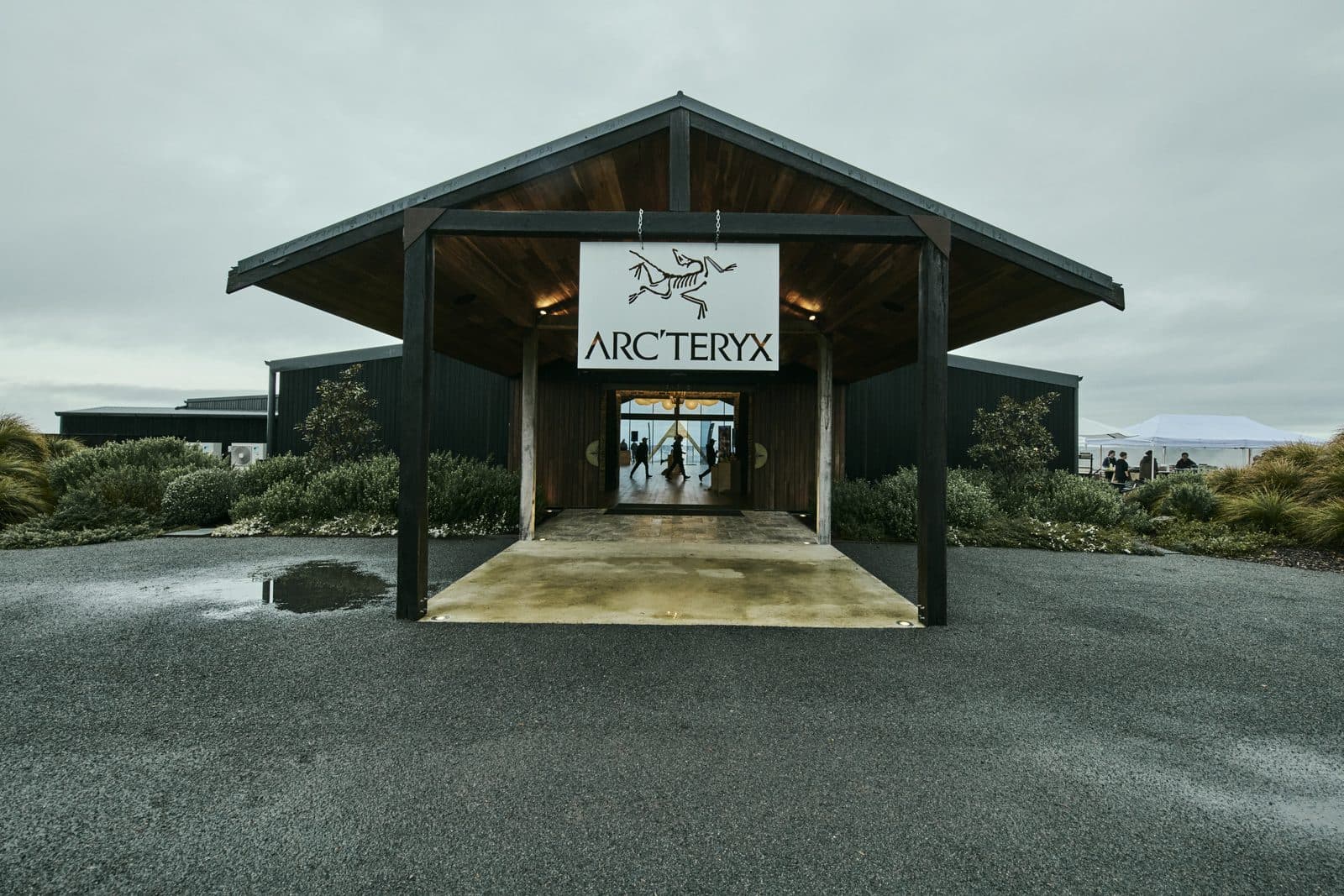 The Pavilion entrance at Caoura Cliffs under an Arc'teryx sign, the forecourt wet from overnight rain