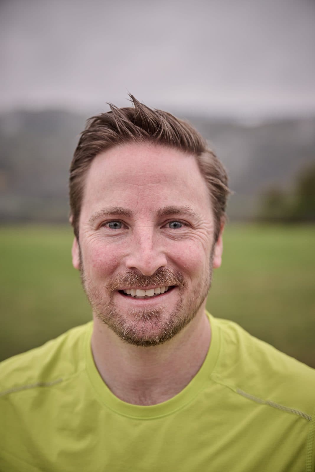 A runner in a lime top smiling on the lawn before the start