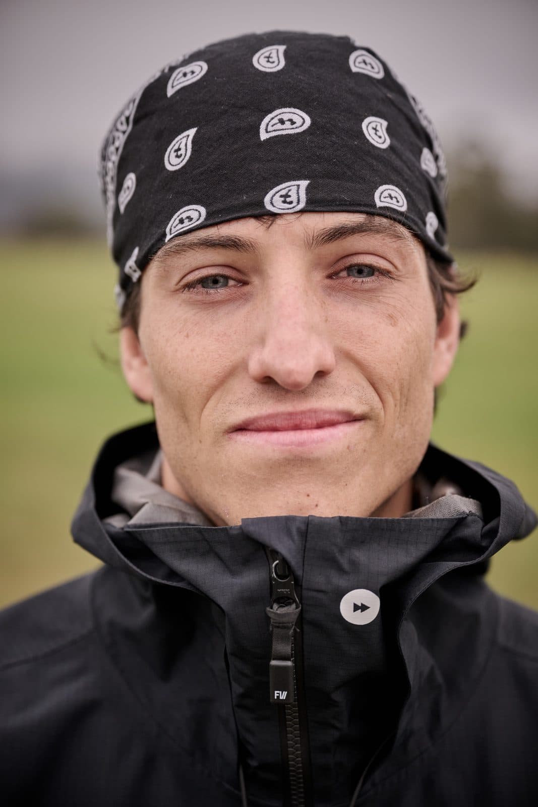 A runner in a patterned bandana and rain shell, fog behind