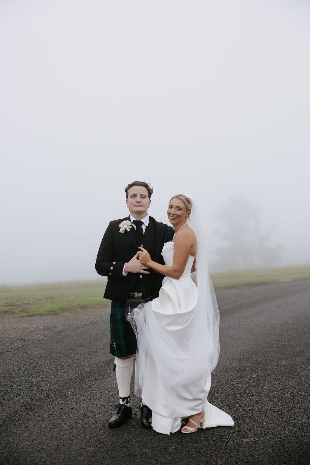 Anna and Calum standing together on the farm road, the fog closing in around them