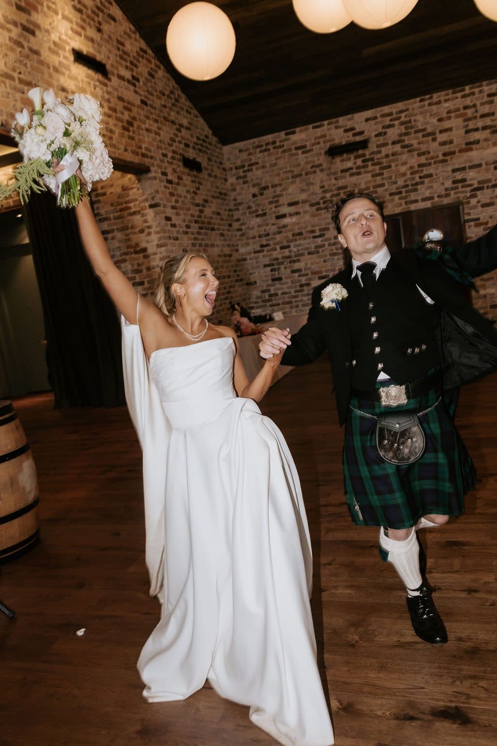 Anna with her bouquet raised and Calum mid-kick as they come into The Pavilion for dinner
