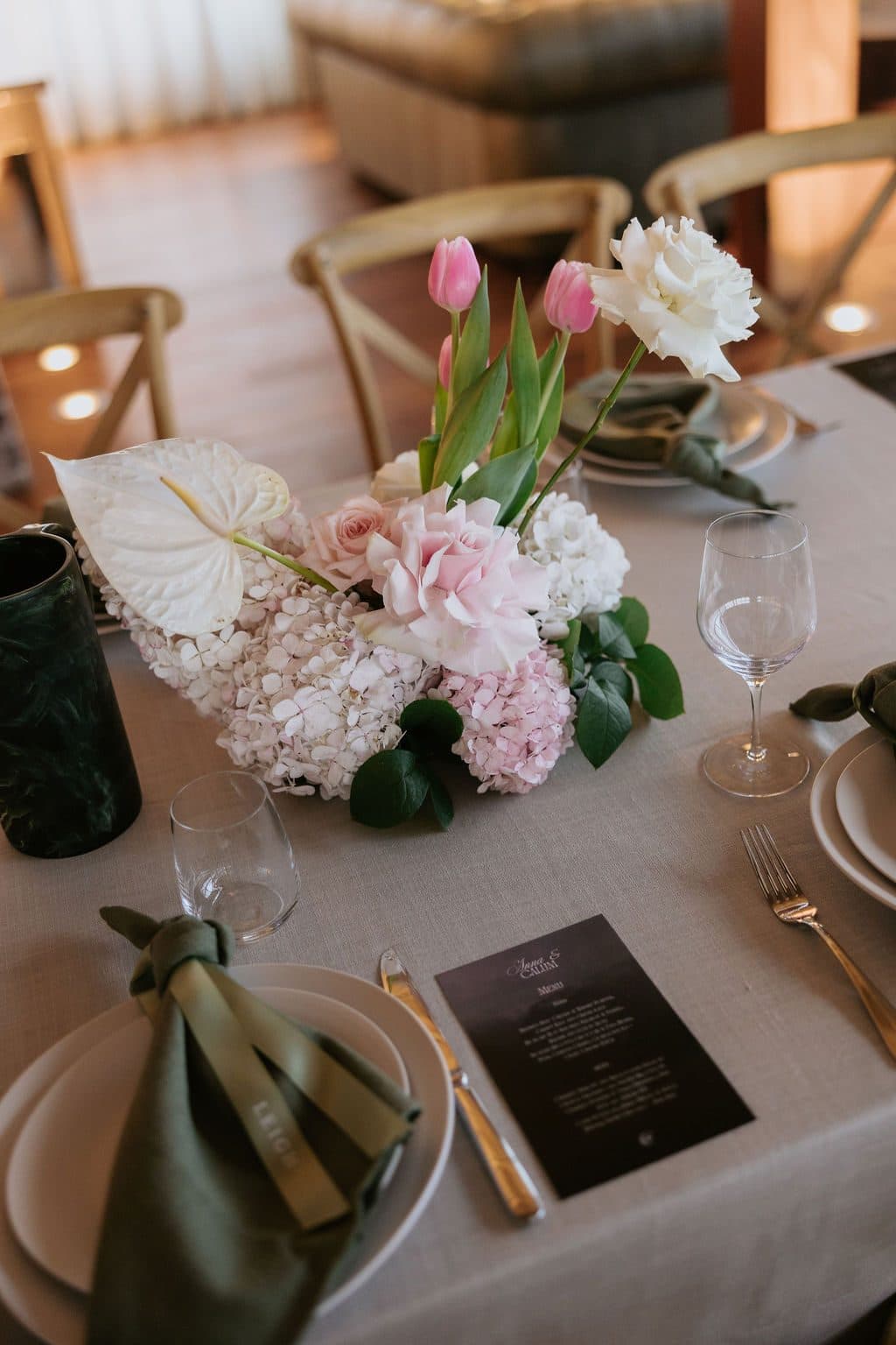 A place setting at dinner, a green linen napkin and tulips on the table