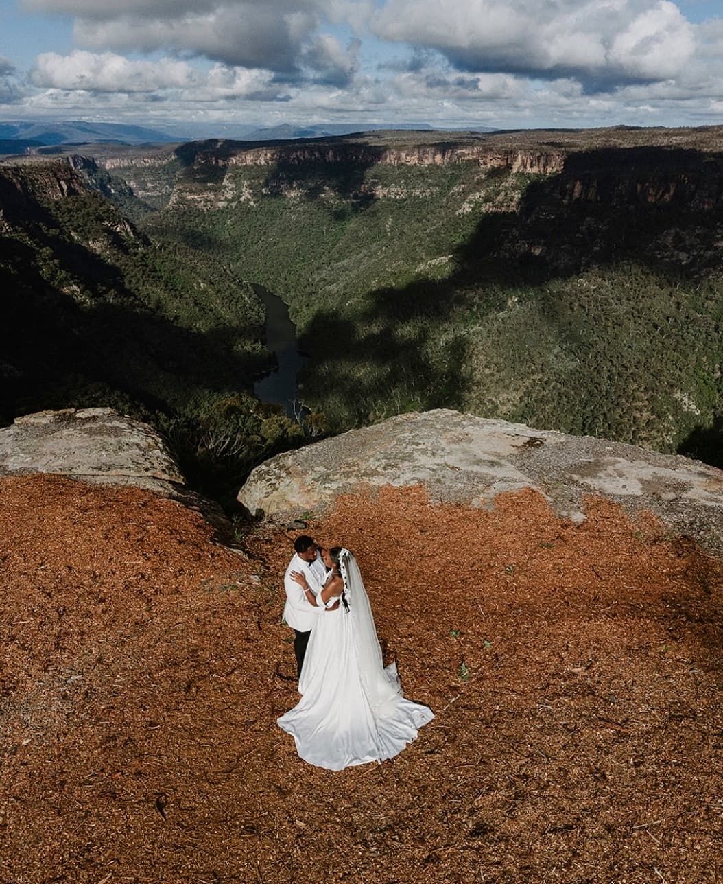 A newly married couple embracing on the cliff edge above the Shoalhaven gorge