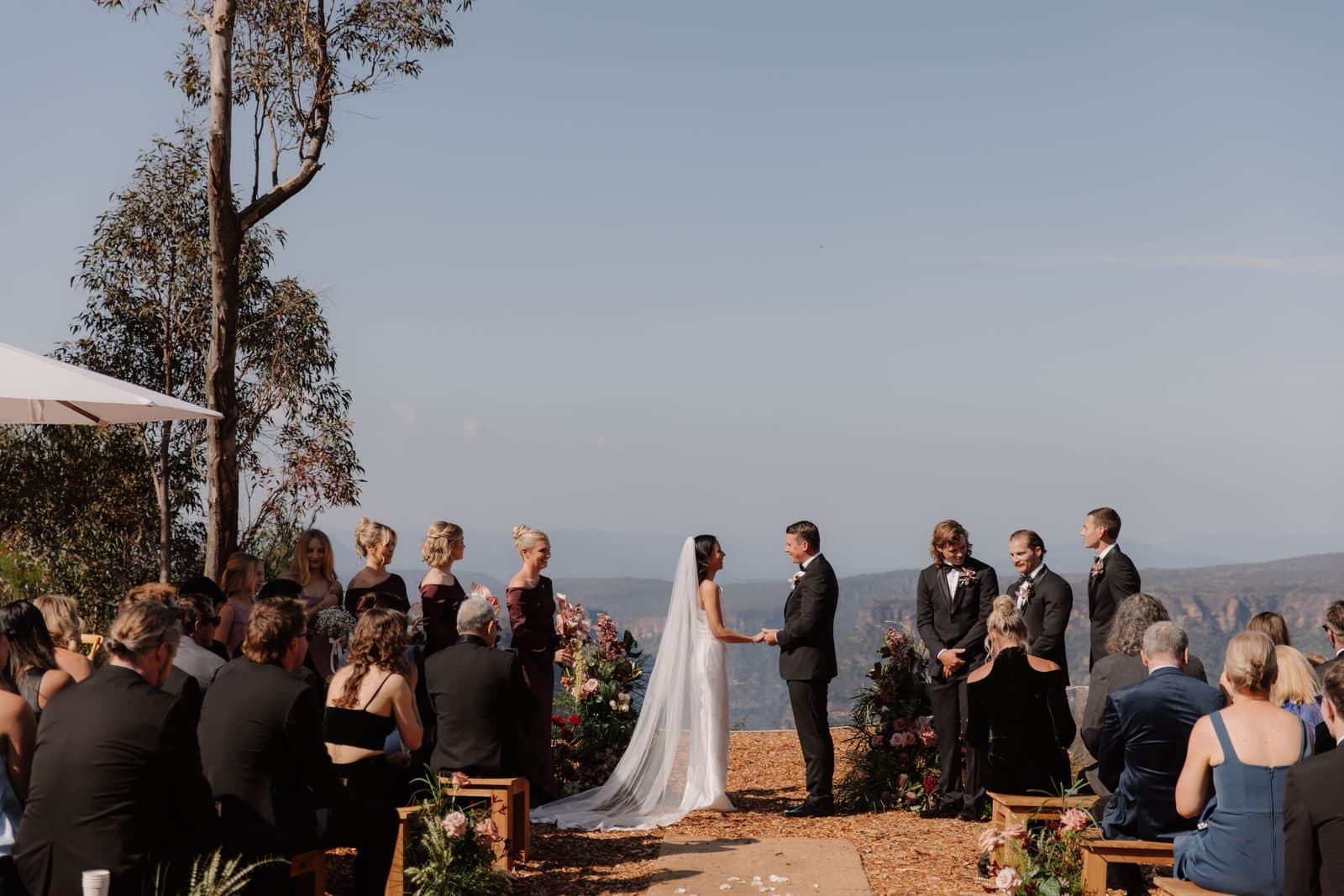 The ceremony at The Cliffs, guests on the timber benches and the gorge running out under a clear sky