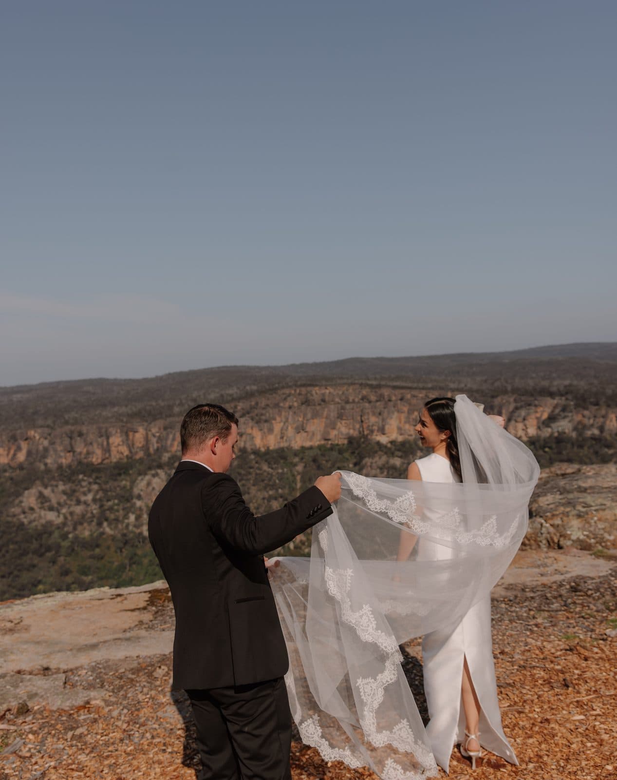 Ben lifting Jamae's veil in the wind at the edge of The Cliffs