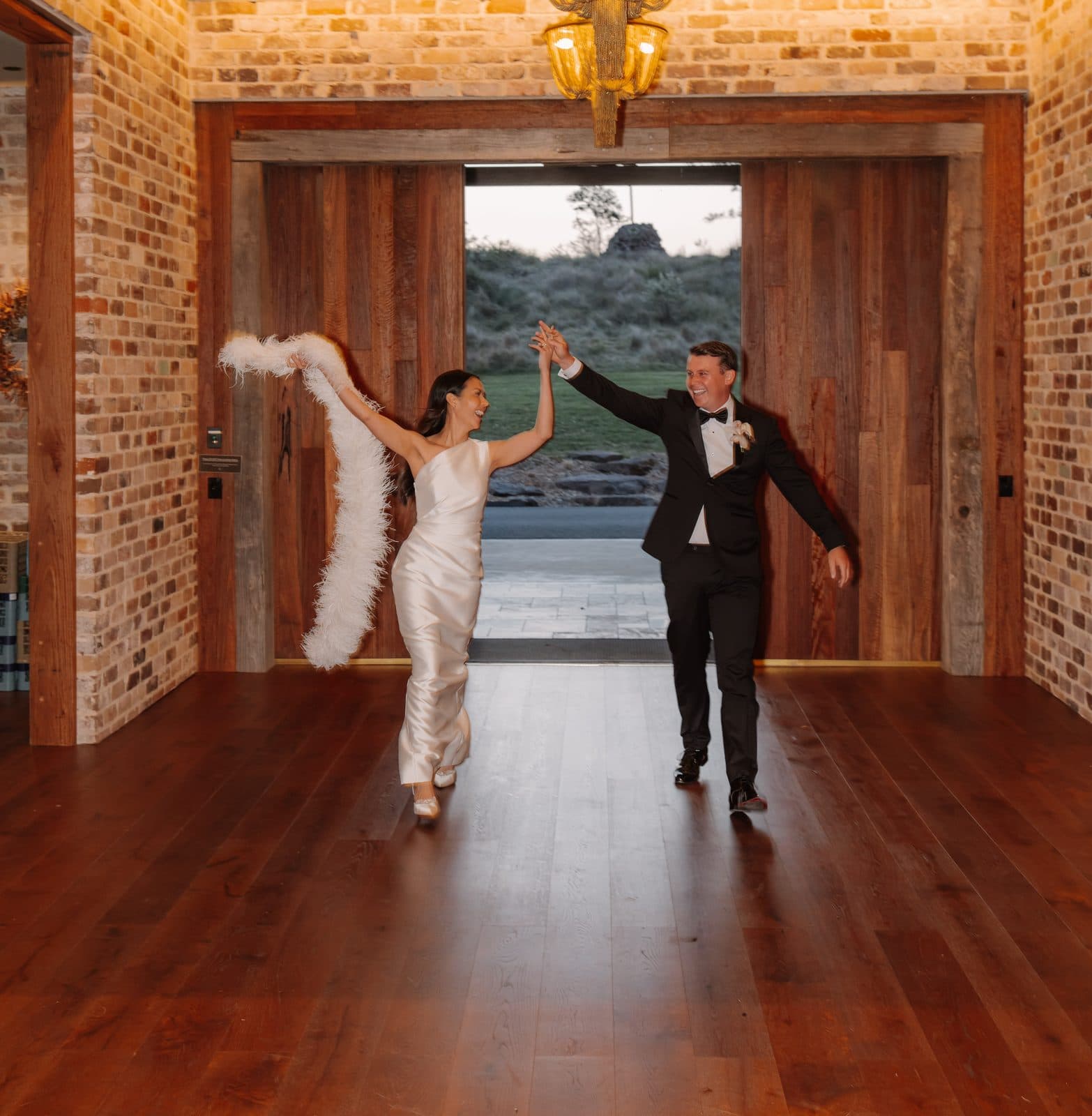 Jamae and Ben making their entrance through the timber doors of The Pavilion, her arm raised