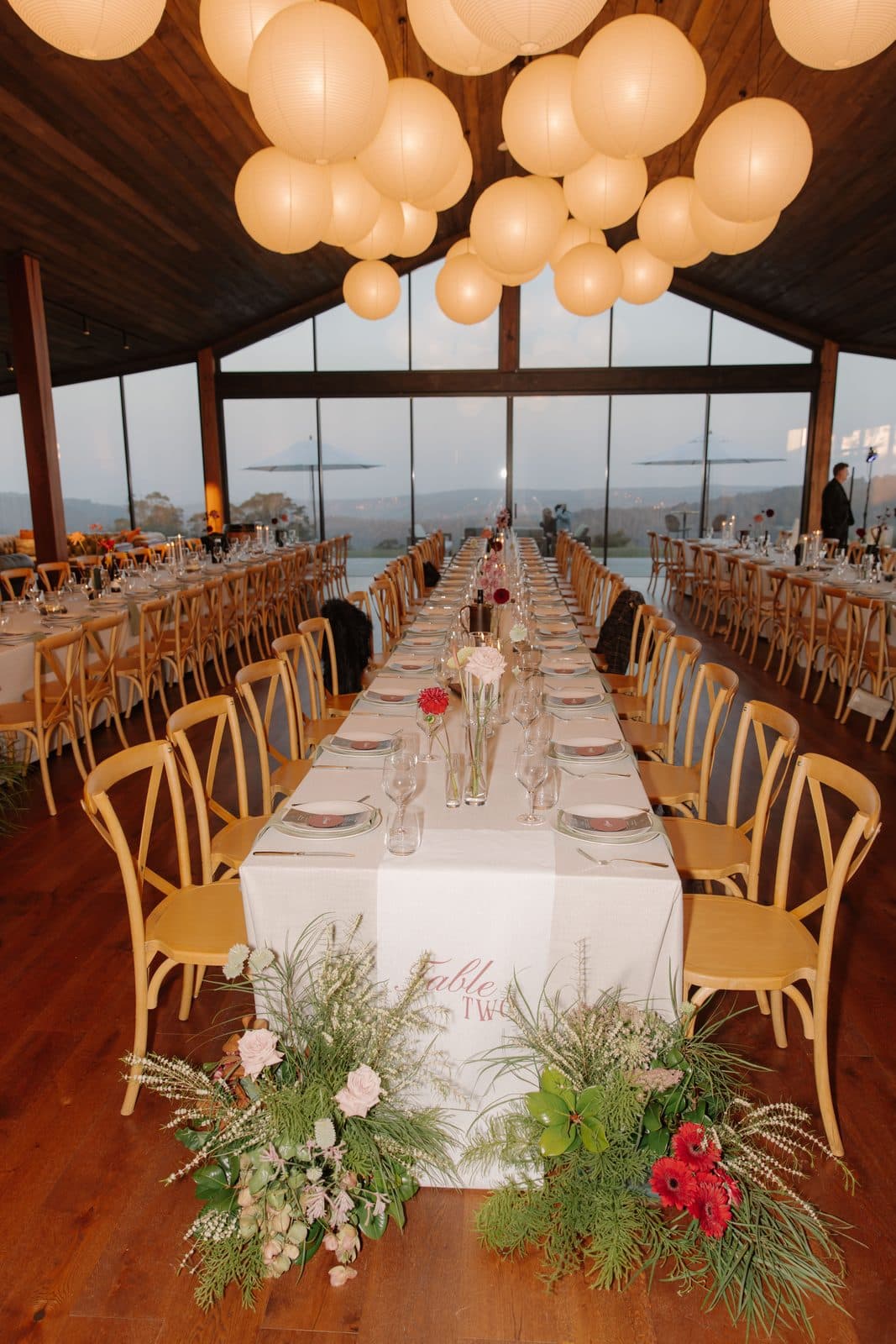 The Pavilion set for dinner under the paper lanterns, shared tables running to the glass