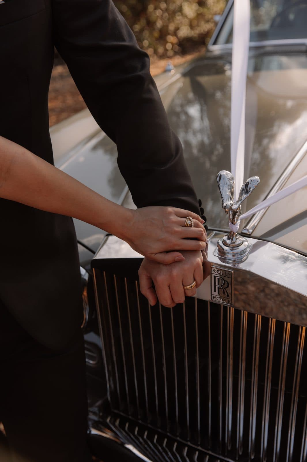 Jamae and Ben's hands resting together on the bonnet of the Rolls-Royce