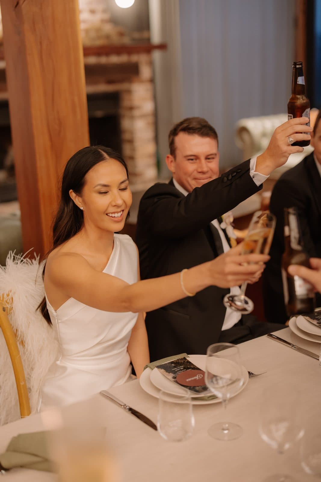 Jamae and Ben raising their glasses at the table during speeches