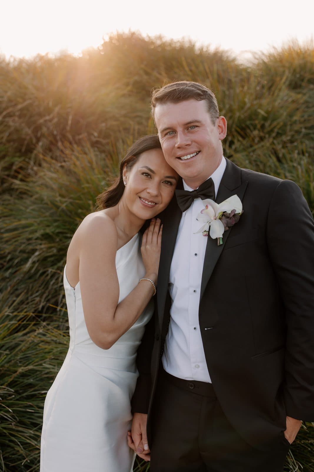 Jamae resting her head on Ben's shoulder among the tussocks in the low gold light