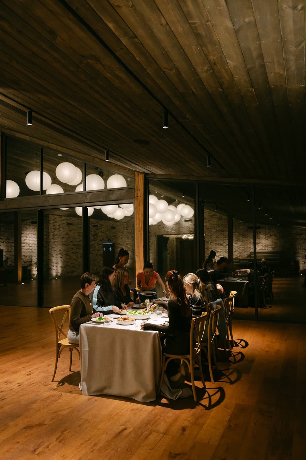 Dinner at the long table in the Pavilion after dark, the lanterns lit above it