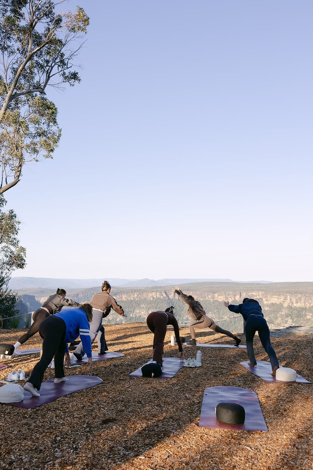 A retreat group moving through a session on the escarpment at sunrise, the gorge beyond