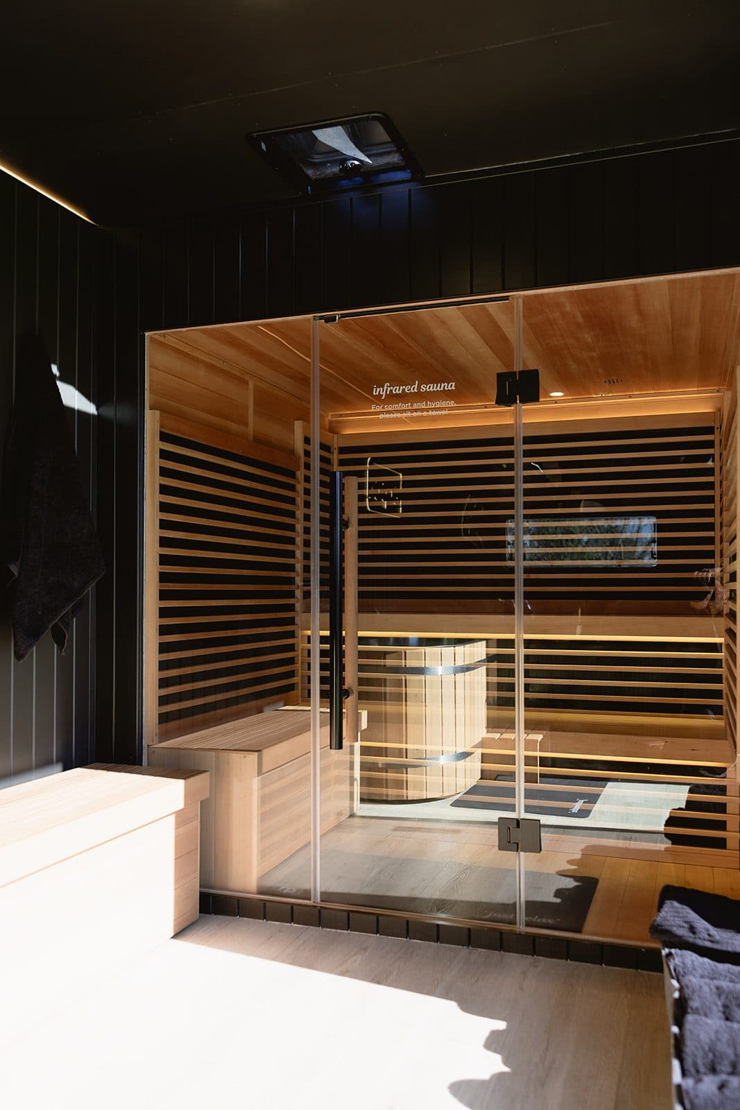 The cedar-lined sauna of the mobile recovery unit, doors open to the paddock