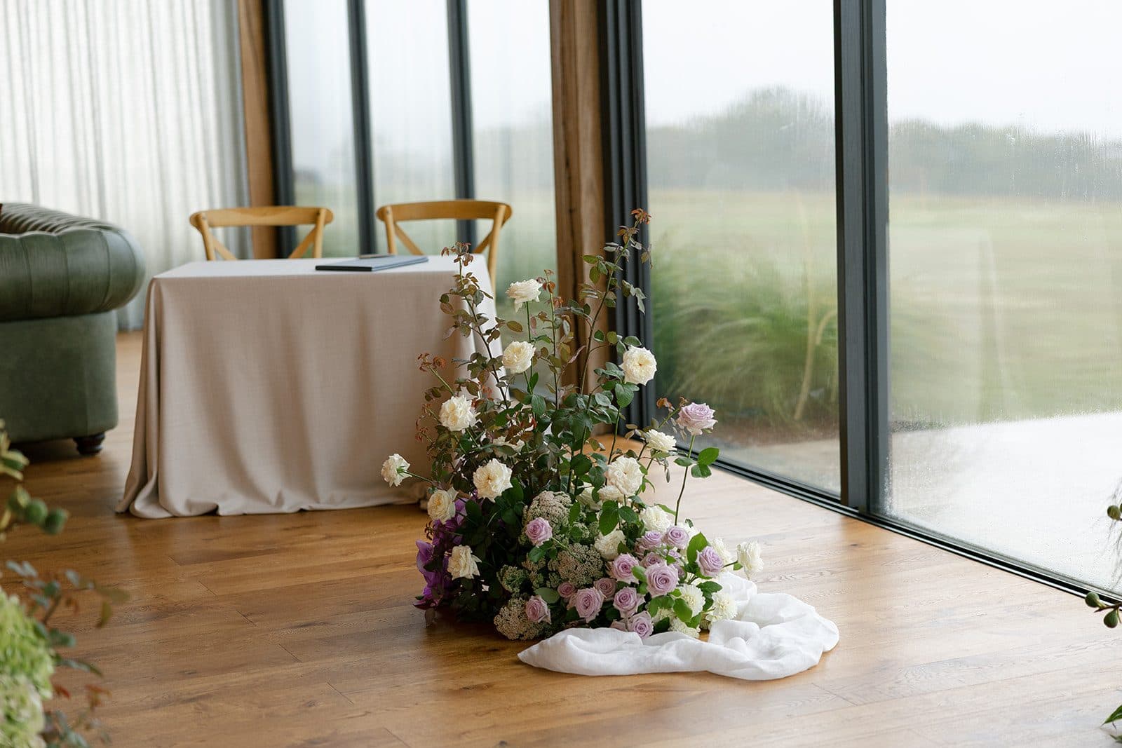 Florals set at the end of the aisle against the Pavilion's glass wall, the wet paddock beyond it