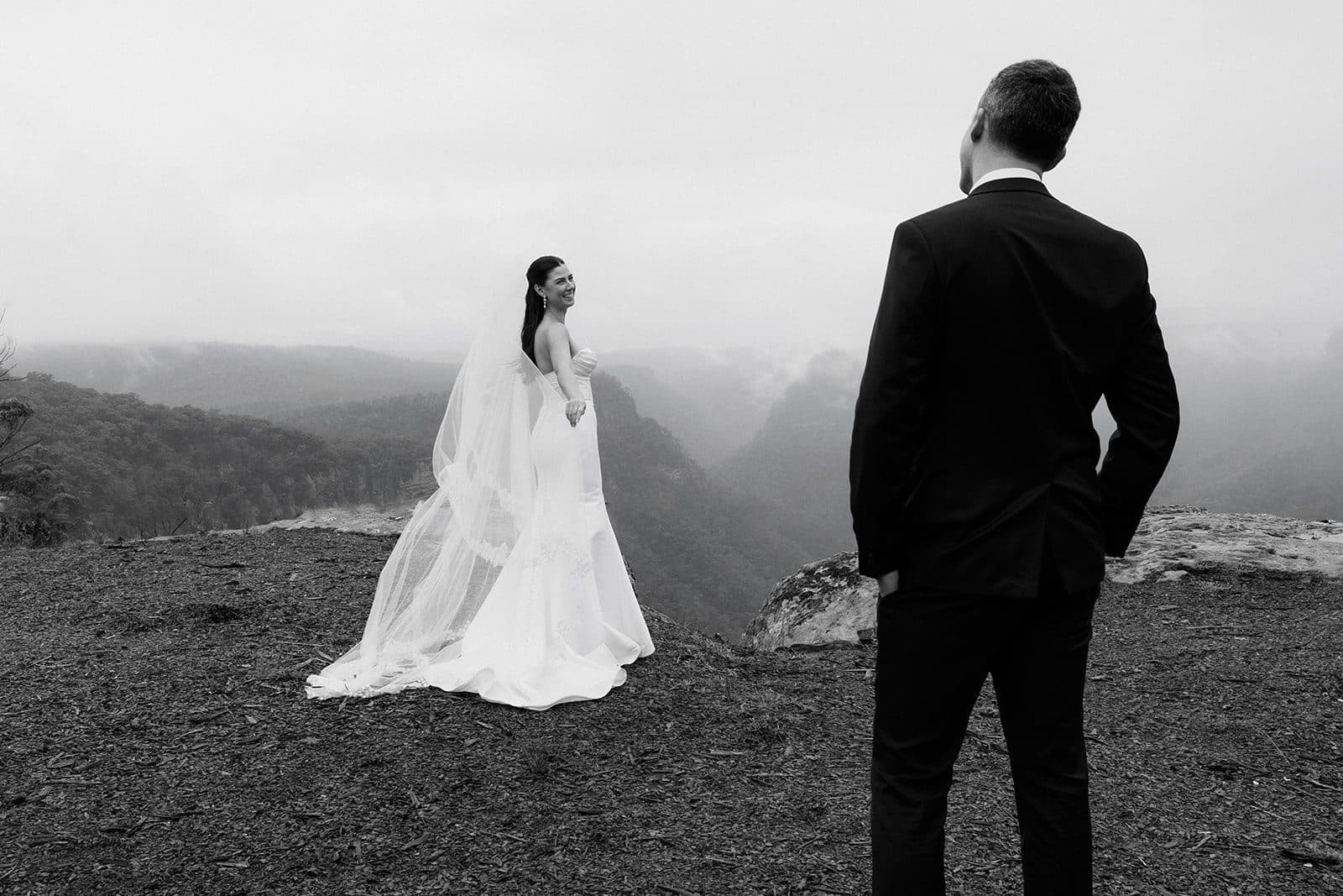 Holly at the edge of The Cliffs looking back over her shoulder, Matt watching from the foreground, the gorge full of cloud