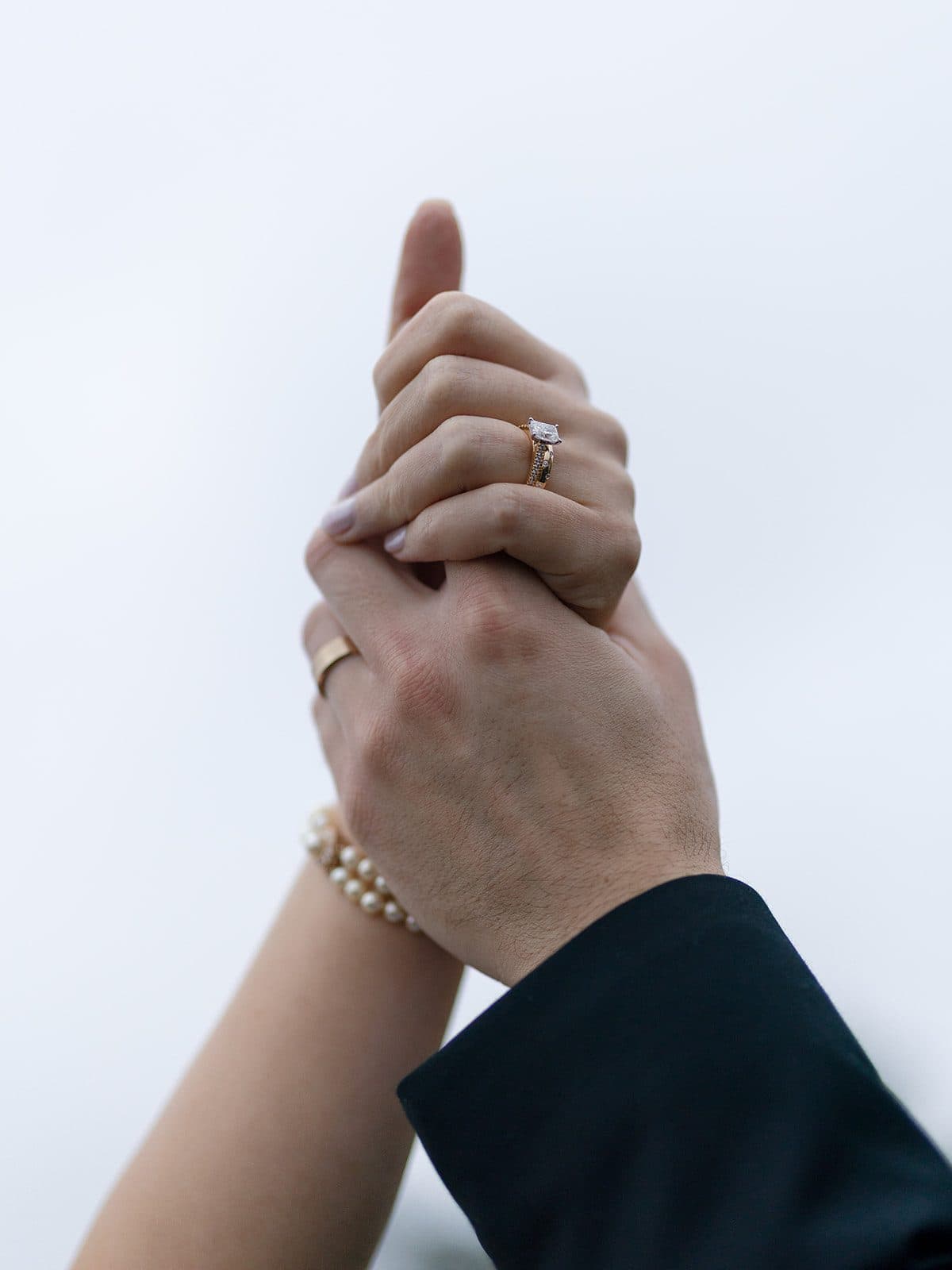 Matt and Holly's hands held together against a white sky