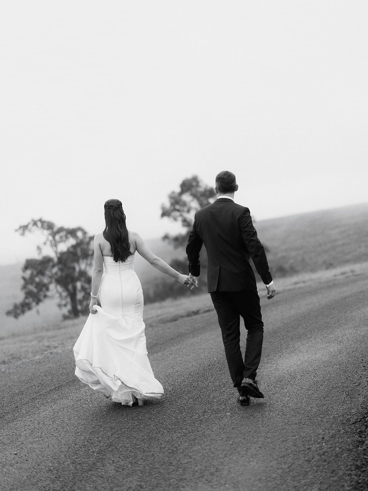 Matt and Holly walking away hand in hand along the track, the treeline behind them in mist