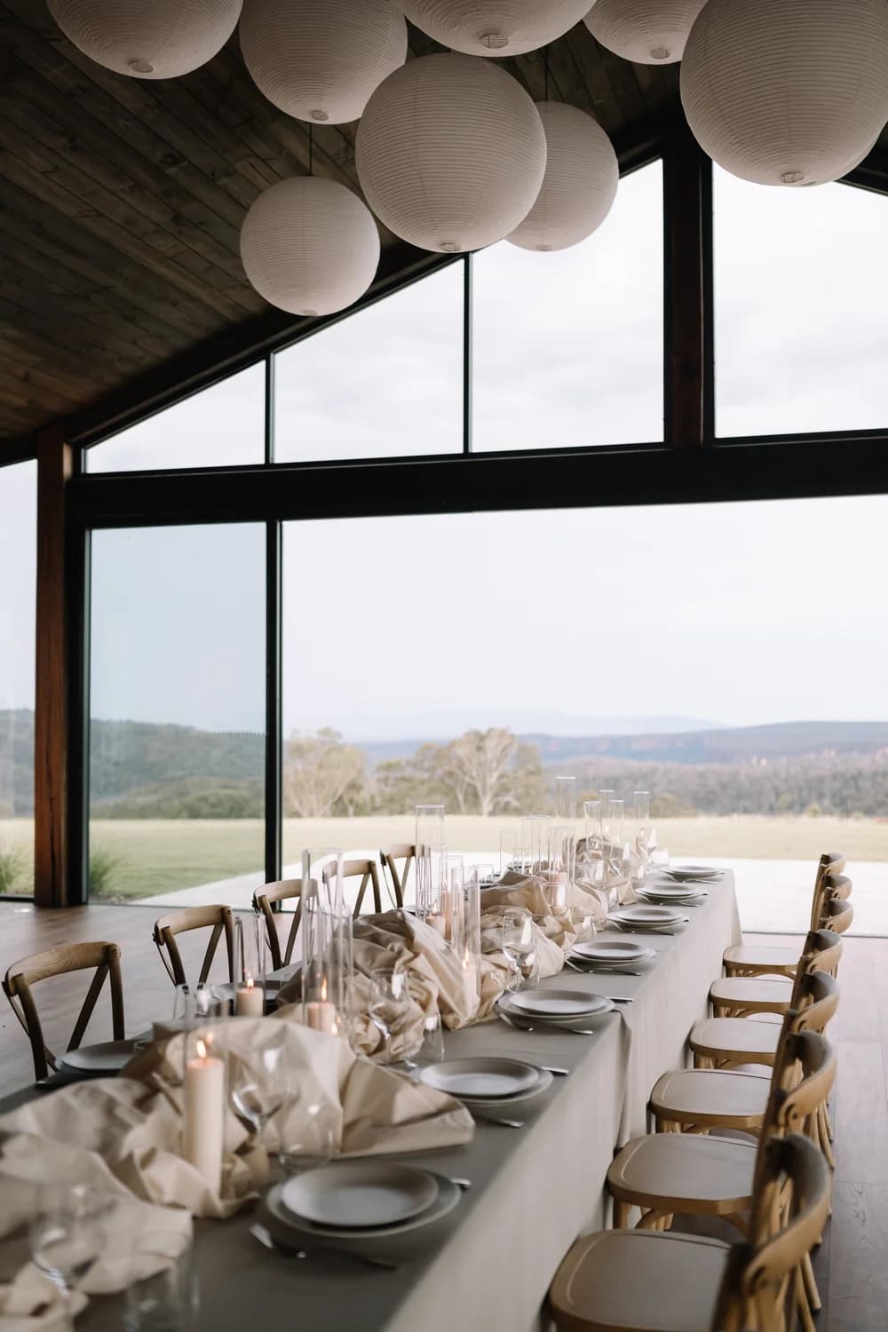 A long table set inside the glass Pavilion, with the escarpment beyond the floor-to-ceiling windows