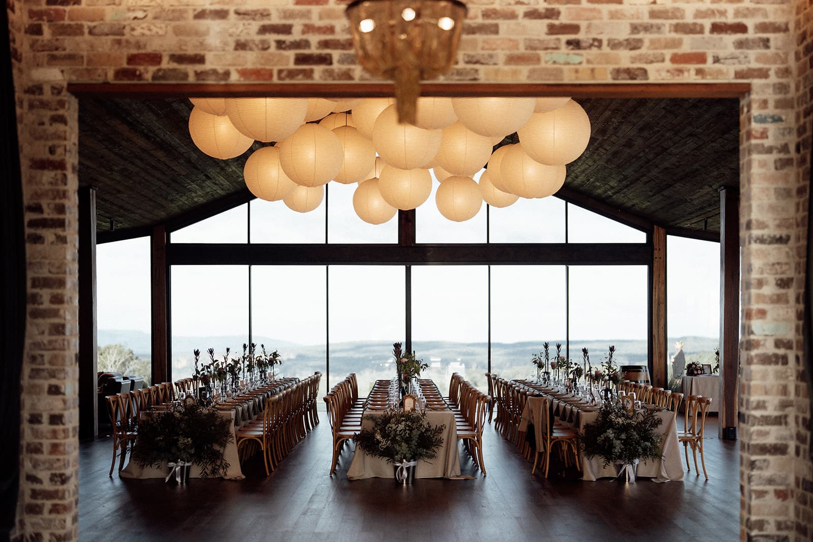 The Pavilion's brick and glass reception room, lit by a cluster of paper lanterns